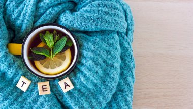 Sıcak atmosfer ve çay konsepti. Yeşil mavi süveter ve ahşap harflerle yapılmış 