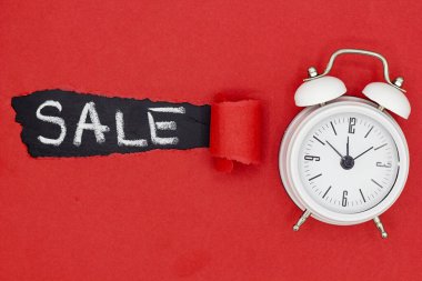 Satış sözcüğünün siyah karatahtaya ve kırmızı yırtık kağıda yazılmış beyaz alarm saatinin üst görünümü