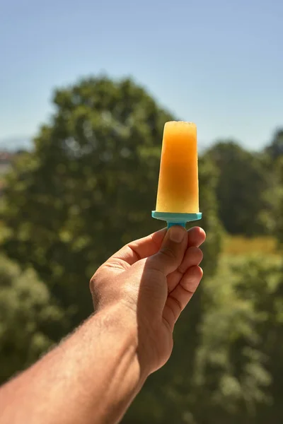 hand with orange ice cream