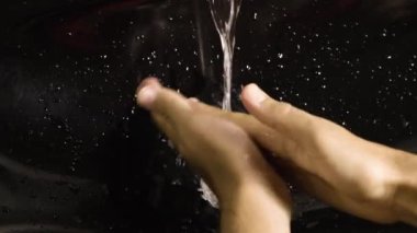 Siyah lavaboda ellerini yıkayan kişi.