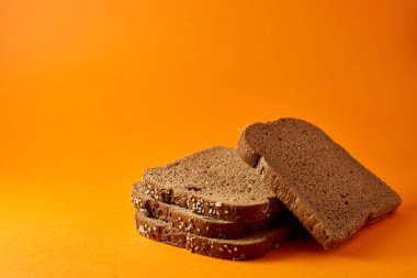 Turuncu arka planda dilimlenmiş buğday tohumu ekmeği.