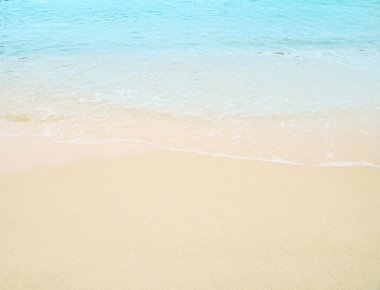 Kumlu sahilde yumuşak bir mavi okyanus dalgası. Arkaplan.