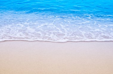 Kumlu sahilde yumuşak bir mavi okyanus dalgası. Arkaplan.
