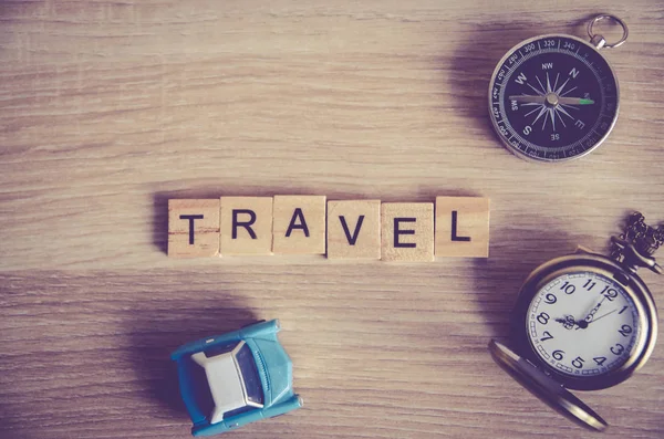 travel concept . travel word on wooden cube block on wood background decoration with compass ,pocket watch and mini car model