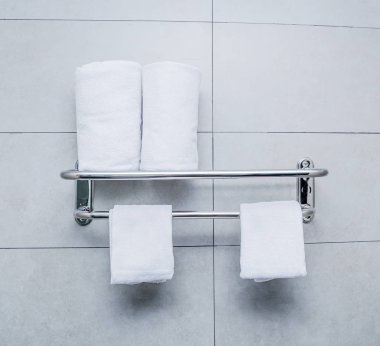 Gri çimento duvarda paslanmaz çelik havlu banyoda kahverengi havlu ile