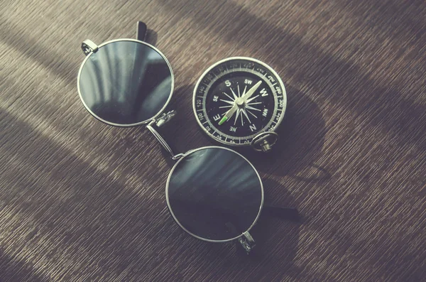 compass and glasses on wood table desk