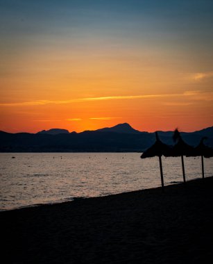 Denizde dağların ardında gün batımı