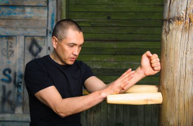 Çin dövüş sanatı olan Wing Chun Kung Fu dövüşçüsü tahta kukla üzerinde çalışıyor.