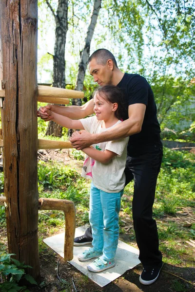 The Chinese martial art of wing Chun Kung Fu fighter is training on the wooden dummy together with the student. Child girl learns martial arts