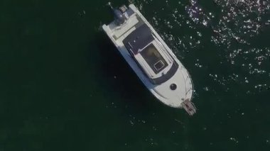 İHA manzaralı tekne yeşil göl kıyısındaki ahşap iskelenin yanında duruyor. Nehir havası görüntülerinde parktaki ahşap tekneler.