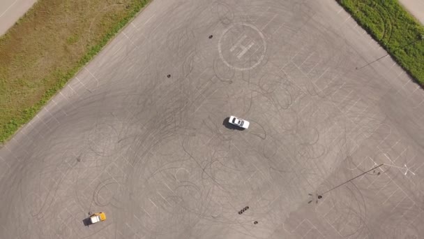 Bilen kör i cirklar på en allmän parkeringsplats, Aerial Drone skott. — Stockvideo