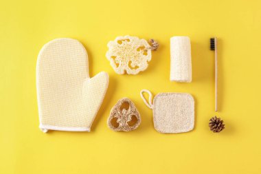 Çevre dostu banyo aksesuarları, banyo aletleri, doğal bambu diş fırçası, sünger. Sarı üzerine sıfır atık kozmetik ürünü.