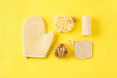 Sarı yüzeyde farklı türde süngerler. Ekolojik lif lifi ve bambu malzemesinden banyo için yeniden kullanılabilir cilt bakımı aletleri. Sıfır atık banyo aksesuarı.