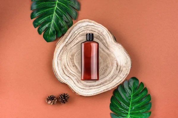 Flacon brun de lotion, crème, shampooing sur coupe transversale en bois coupé avec des feuilles de monstère sur la surface brune. Concept de produit de beauté bio naturel. Conteneur pour produit cosmétique.Mockup — Photo