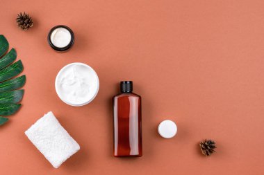 Sağlık salonu kompozisyonu. Kahverengi yüzeyinde doğal bileşenleri olan cilt ürünleri. Açık kavanozda nemlendirici yüz maskesi kremi, sahte losyon şişesi, havlu. Spa konsepti. Boşluğu kopyala