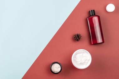 Şampuan ya da kozmetik losyon şişesi çerçevesi, yüz kremi kavanozu, kozalak. Mavi ve kahverengi yüzeyde cilt bakım ürünleri. Güzellik kompozisyonu. Doğal kozmetik konsepti. Düz, düzlem, boşluğu kopyala
