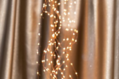 Altın perdelerde sönmüş ışıklarla sıcacık çelenkler arka planda, şenlikli dekorasyonlar. Parlak ışıkları olan soyut sarı desen.