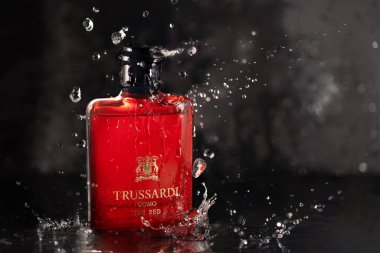 Parfüm Trussardi şişesi taştan duvara karşı koyu taştan arka plandaki su damlalarının altında. Yeni bir başlangıç için erkek parfümü.