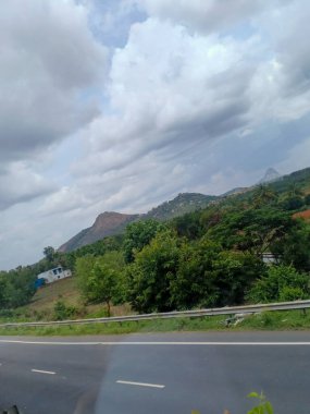 dağlar ve hindistan cevizi ağaçları yol kenarından görünüyor.