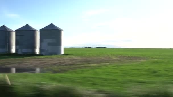 在加拿大艾伯塔省的大草原上 沿着最近种植的带有大型金属粮仓的田地驱车而过 凸显了农业的重要性 — 图库视频影像