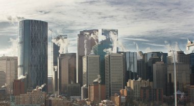 Calgary Alberta Canada, 7 Haziran 2020: Şehir gökdelenleri, bahar sabahının erken saatlerinde çatılarındaki buhar egzozlarını havalandırıyor ve iş dünyası yoğun bir iş günü için toplanıyor..