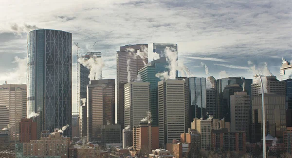 Calgary Alberta Canada, 7 Haziran 2020: Şehir gökdelenleri, bahar sabahının erken saatlerinde çatılarındaki buhar egzozlarını havalandırıyor ve iş dünyası yoğun bir iş günü için toplanıyor..