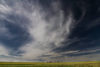 Rocky View County Alberta Canada 'nın ovalarında bir çiftlik arazisi üzerinde dramatik bulutlu bir gökyüzü..
