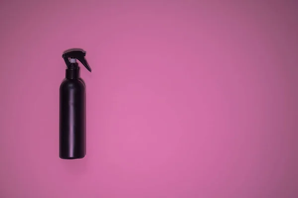 粉色背景的黑色瓶子里喷着美丽的发胶 — 图库照片