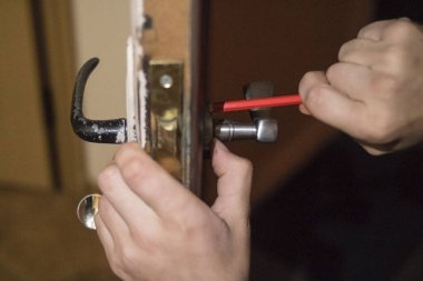 Tecrübeli bir adam eski kahverengi kapıları tamir eder.