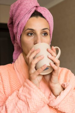 Güzel esmer kız mutfakta kahve içiyor.