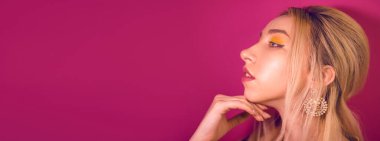 Sarı saçlı, sarı makyajlı, pembe arka planda bir kız.