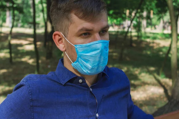 Ένας Τύπος Ιατρική Μάσκα Κάθεται Ένα Ξύλινο Παγκάκι Στο Πάρκο — Φωτογραφία Αρχείου