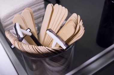 Tek kullanımlık tıraş bıçakları ve merhem sürmek için tahta çubukları olan şeffaf cam.