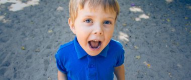 Kum arka plandaki küçük sarışın çocuk.