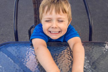 Sandalyede oturan küçük sarışın çocuk.