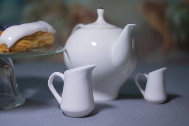 Gri masada beyaz çaydanlık ve beyaz süt sürahisi