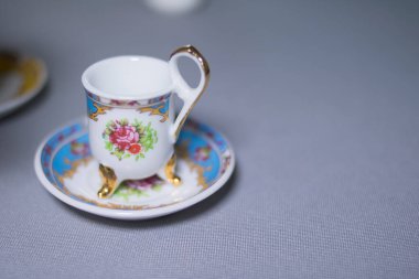 Gri masada küçük beyaz ve mavi fincan ve tabak.