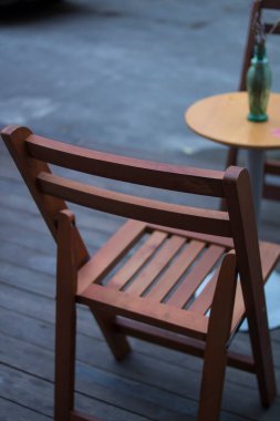 Kafe terasında küçük masa ve tahta sandalyeler.