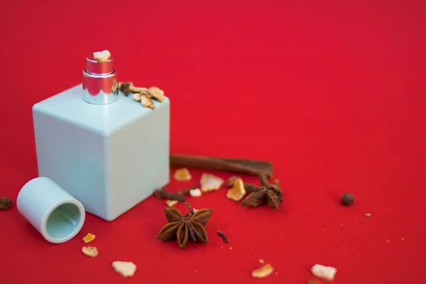 蓝色的香水瓶 带有肉桂 星形茴香和橙皮的红色背景 — 图库照片