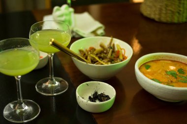 Beyaz ejderha kokteyl bardakları, bir tabak Tom yer elması, cırcır böcekleri ve ahşap masada domuz kulağı salatası.