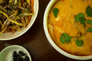 Tom leziz, domuz kulaklı salata ve tahta bir masada bir tabak cırcır böceği.