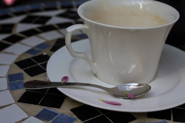 一只空的白咖啡杯立在桌子上 桌上摆满了马赛克 — 图库照片