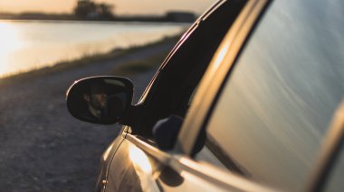 Arka planda gün batımı olan bir araba.