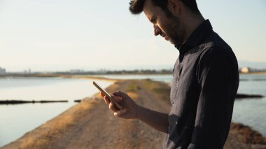 Doğanın ortasında cep telefonuna bakan bir adam.