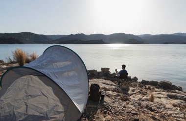 Çocuk gölde kamp yapıyor.