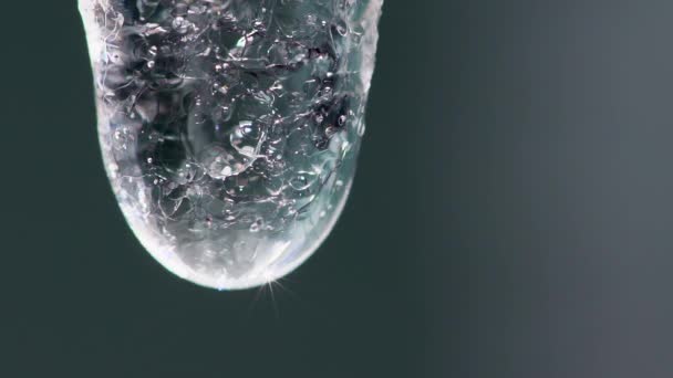 Super close-up slow motion video of a crystal drop dripping from an icycle — Stock Video