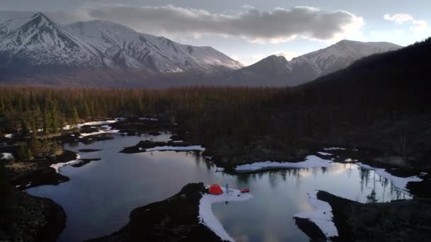 Tiro aéreo de um acampamento com caminhante cercado por lago em montanhas — Vídeo de Stock