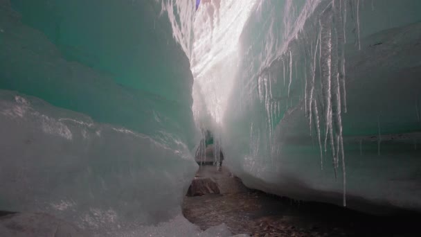 Ice block with dropping icicles and stream running under it — Stock Video