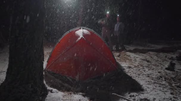 Ein Paar, das sich in einer verschneiten Nacht auf einem Campingplatz unterhält — Stockvideo