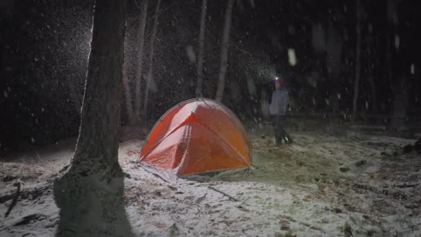 Kobieta stojąc przed czerwonym namiocie w snowy nocy — Wideo stockowe